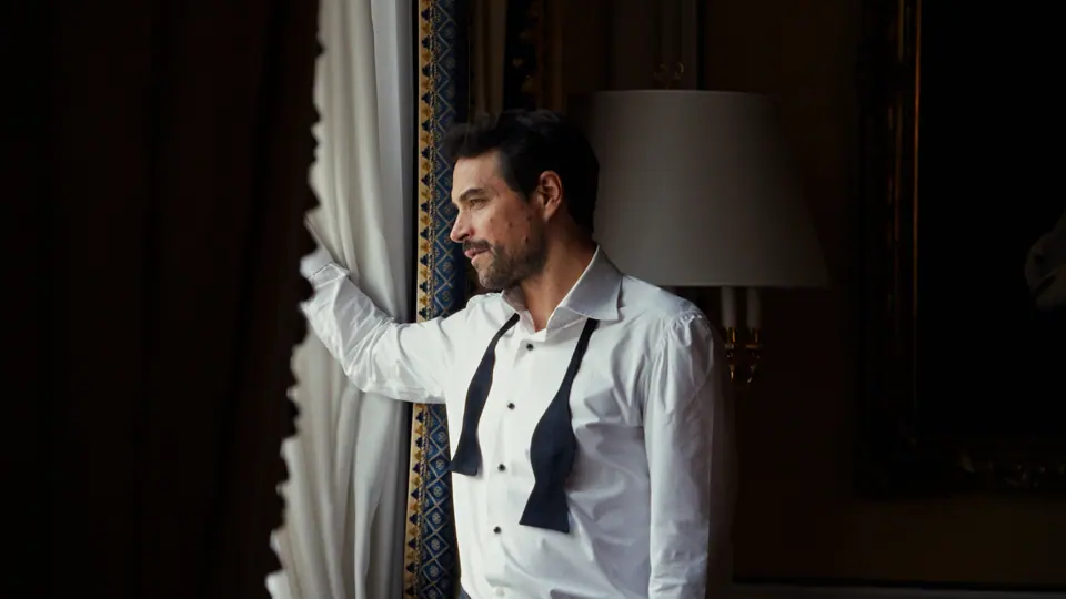 Groom standing by a window at Hotel Imperial