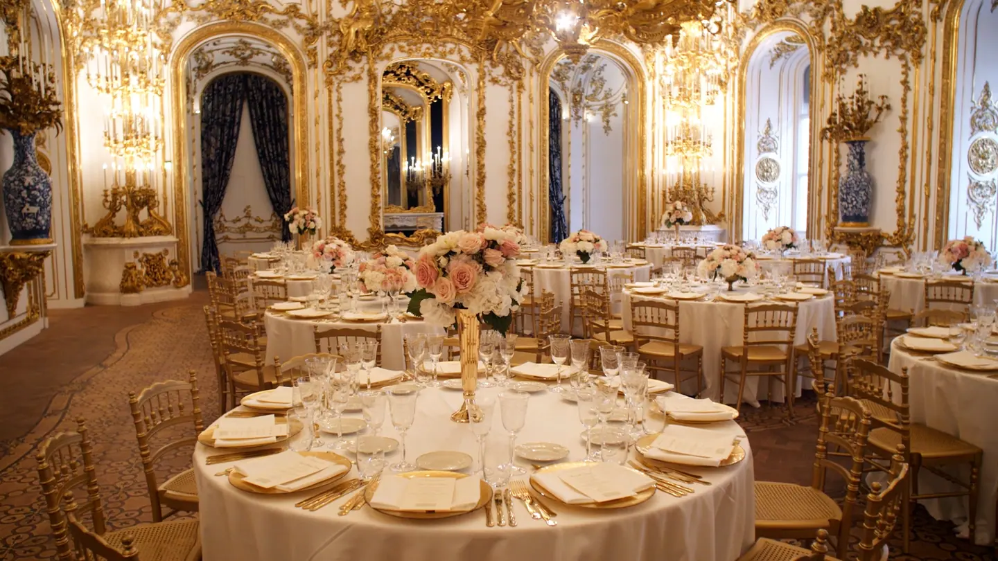Gold and white palace ballroom prepared for a wedding dinner