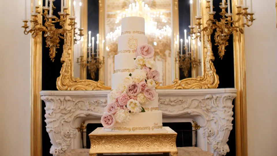 Elegant white wedding cake with blush flowers and gold details