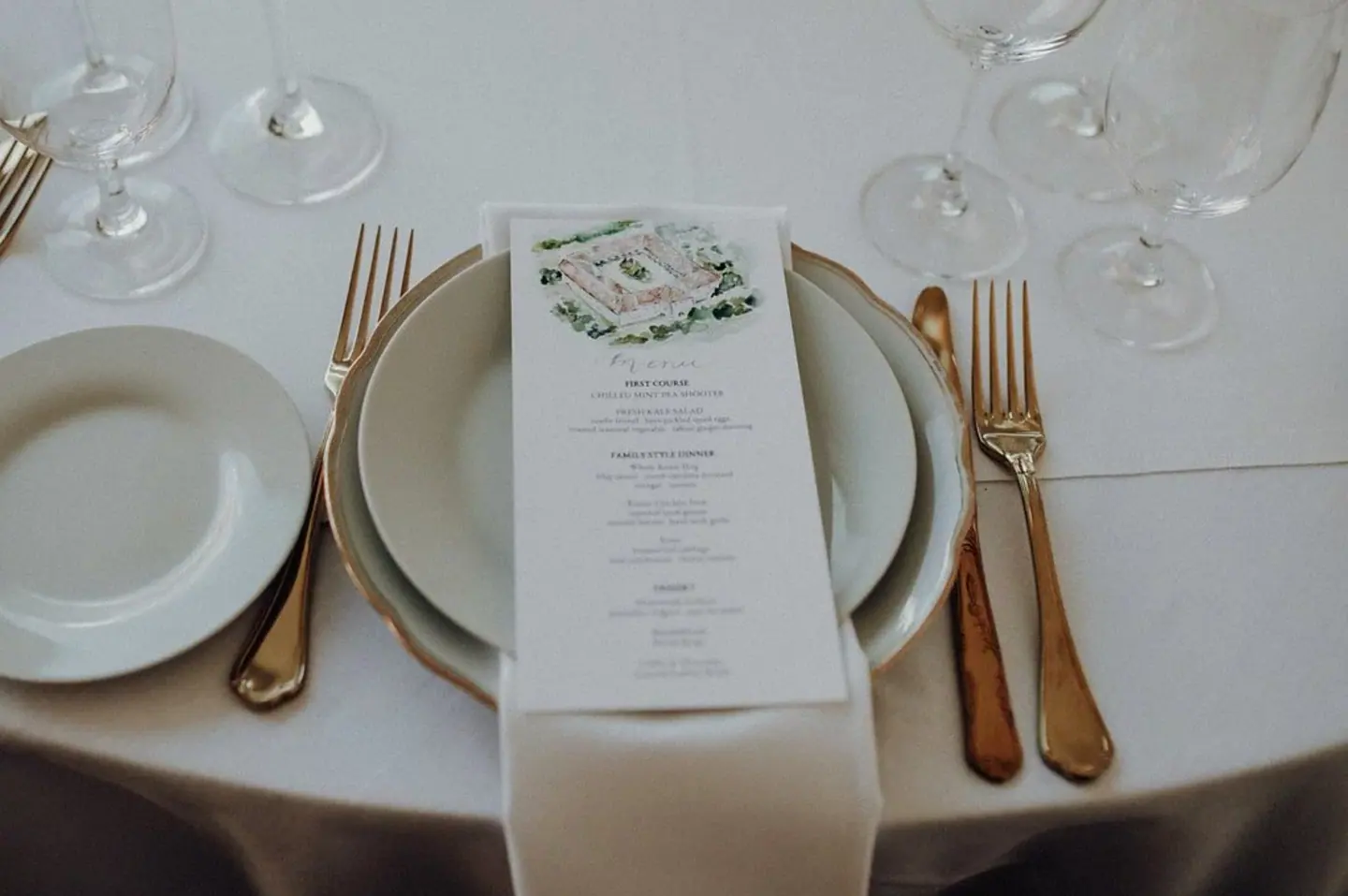 Wedding table setting with illustrated menu and gold flatware