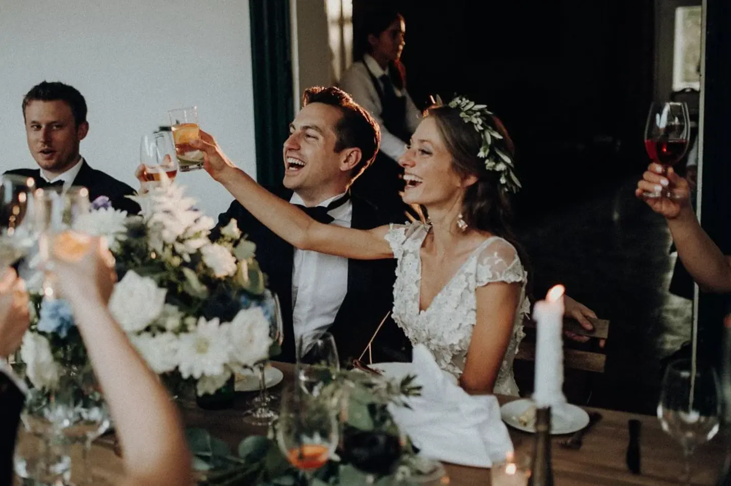 Bride and groom laughing during a toast at dinner